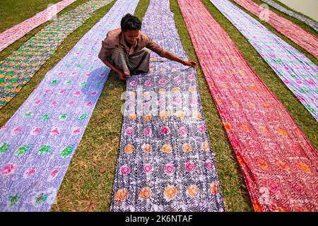 Les employés sèchent des chiffons colorés en rangées nettes sur un champ. Les tissus sont localement appelés 'Saree' - un vêtement traditionnel pour les femmes. Banque D'Images