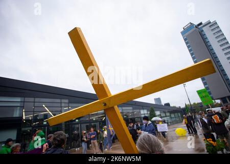 Bonn, Allemagne. 14th octobre 2022. Une croix en bois jaune est maintenue par les manifestants avant le début de la convention nationale du Parti Vert à Bonn au Centre mondial des conférences. Credit: Thomas Banneyer/dpa/Alay Live News Banque D'Images