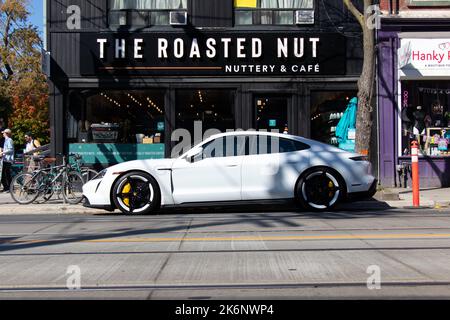 Une Porsche Taycan blanche, le premier modèle de véhicule électrique de Porsche, est garée au centre-ville de Toronto par une journée ensoleillée. Banque D'Images