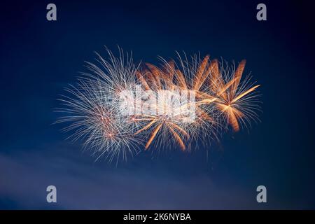 Gros plan sur l'explosion des feux d'artifice avec des étoiles blanches et orange. Isolé sur le ciel noir et bleu de nuit. Idéal pour Sylvester et le nouvel an. Banque D'Images