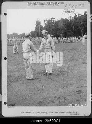 Brig. Le général Paul B. Wurtsmith, commandant 5th Fighter Command, félicite le capitaine Ray Melikian, Fresno, Californie, du groupe Fighter 49th, après l'avoir présenté avec la Croix de vol distinguée, lors d'une cérémonie tenue à l'aérodrome de Dobodura, (Horando) Banque D'Images