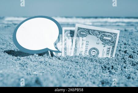 Billets de papier un dollar, un petit bâton propre papier vide bulle de parole enfouie dans le sable plage arrière-plan mer gros plan dans la journée ensoleillée d'été. Concept argent voyage tourisme vacances. Bleu blanc Banque D'Images