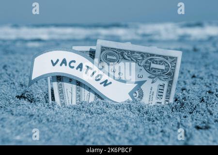 Billets de papier un dollar et un petit bâton avec la bulle de la parole de papier avec le mot vacances enterrées dans le sable plage arrière-plan mer gros-up ensoleillé jour d'été. Concept argent voyage tourisme vacances Bleu blanc couleur Banque D'Images