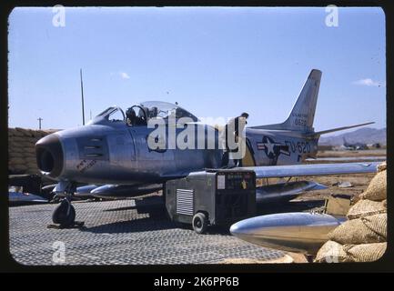 Vue de trois quarts avant gauche d'un sabre F-86E nord-américain, « Mach Knocker » (n/s 50-620; n/s 170-42). L'art du nez inclut le surnom et un défilement avec l'écriture sur lui. Le pilote est dans le poste de pilotage, un technicien est debout sur l'aile tenant un flexible. Une unité d'alimentation électrique se trouve à côté de l'avion. Vue de trois quarts avant gauche d'un sabre F-86E nord-américain, « Mach Knocker » (n/s 50-620; n/s 170-42). L'art du nez inclut le surnom et un défilement avec l'écriture sur lui. Le pilote est dans le poste de pilotage, un technicien est debout sur l'aile tenant un flexible. Une unité d'alimentation électrique se trouve à côté de l'avion. Banque D'Images