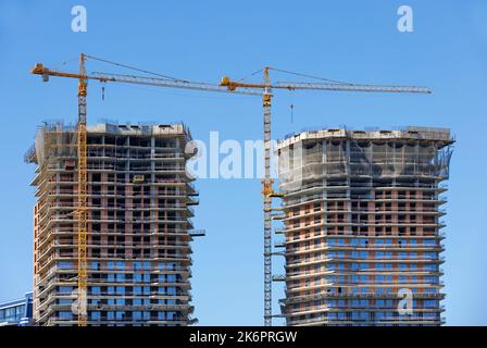 Construction moderne de tours jumelles de plusieurs étages de bâtiments résidentiels avec l'aide de grues de tour, le jour d'été. Banque D'Images