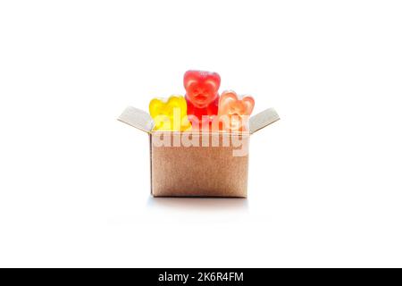 Boîte d'expédition miniature pleine de bonbons d'ours en gelée colorés isolés sur fond blanc. Acheter des chérie en ligne. Banque D'Images