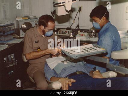 Lieutenant Gary Brown, dentiste, et un dentiste sur l'USS Dwight D. Eisenhower (CVN-69)'en mer… Lt. Gary Brown, dentiste, et un dentiste travaillent sur les dents d'un patient dans les espaces dentaires du porte-avions à propulsion nucléaire USS Dwight D. Eisenhower, CVN-69.' Photographe : ph3 C.L. Youmans. Banque D'Images