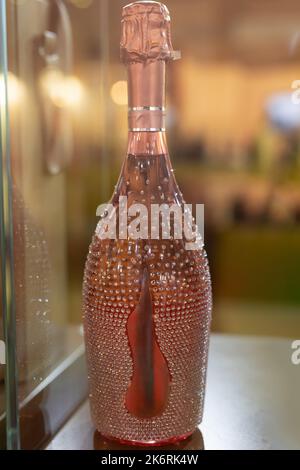 Bouteille de champagne rose étincelante décorée de paillettes. Banque D'Images