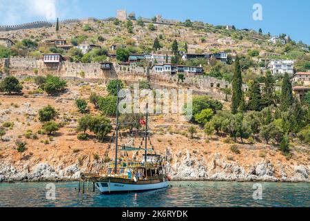 Alanya, Turquie – 19 août 2021. Côte à Alanya, Turquie. Vue sur un bateau gulet, les bâtiments résidentiels et les anciens murs du château. Banque D'Images