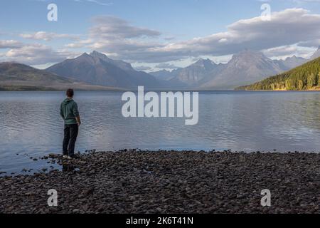 Homme debout sur le rivage et regardant les montagnes étonnantes de l'autre côté du lac McDonald dans le parc national des Glaciers Banque D'Images