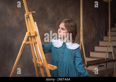 une petite fille mignonne tire derrière un chevalet. rêvant Banque D'Images