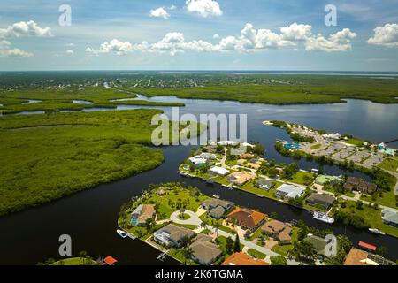 Vue aérienne des banlieues résidentielles avec maisons privées situées près des terres humides sauvages avec végétation verte sur la rive de la mer. Vivre à proximité de la nature concep Banque D'Images