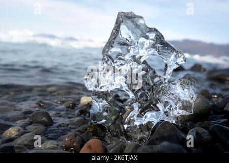 Glace, morceau de glace avec trou sur la plage de gravier noir, glacier lagon Joekulsarlon, lac glaciaire, bord sud de Vatnajoekull, sud-est de l'Islande Banque D'Images