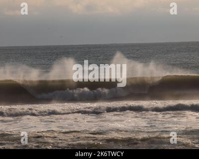 La tempête a lancé des vagues qui se sont écrasées contre la côte du New Jersey et le vent a soufflé sur leurs sommets. Rétroéclairées, les courbes apparaissent transparentes. Banque D'Images