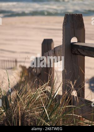 Le vent a fané la clôture sur un chemin vers la plage au-dessus d'une dune de sable. Banque D'Images