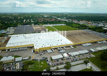 Vue de dessus du centre logistique géant avec de nombreux camions de remorques commerciales qui déchargent et chargent des produits de vente au détail pour une expédition ultérieure. Co. Économie mondiale Banque D'Images