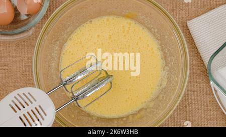 Recette de gâteau aux pommes avec base de biscuit, processus de cuisson étape par étape.Mélanger les œufs et le sucre dans un bol en verre, poncer à plat.Gros plan des ingrédients sur la languette de la cuisine Banque D'Images