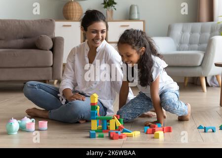 Une femme et une fille indiennes jouent sur des blocs de bois assis sur le sol Banque D'Images