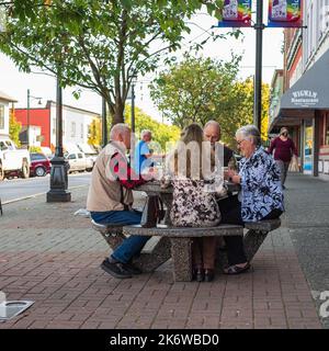 Retraite active, personnes âgées et personnes âgées temps libre, groupe de quatre hommes âgés ayant du plaisir et jouant au jeu de cartes au parc. Photo de rue, foyer sélectif Banque D'Images