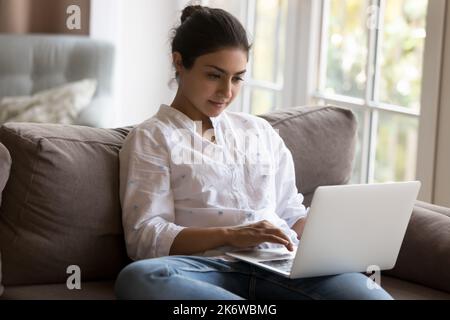 Femme indienne attirante et ciblée utilisant un ordinateur portable à la maison Banque D'Images