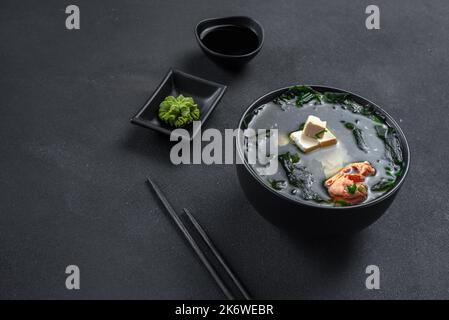 Soupe asiatique traditionnelle sur fond noir. Soupe miso au saumon Banque D'Images