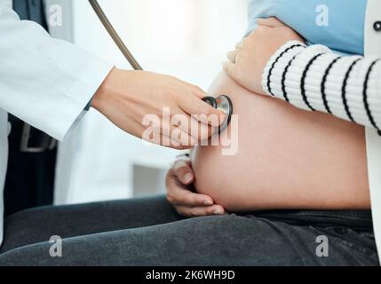 .un médecin méconnaissable utilisant un stéthoscope sur un estomac de femme enceinte pendant un examen. Banque D'Images
