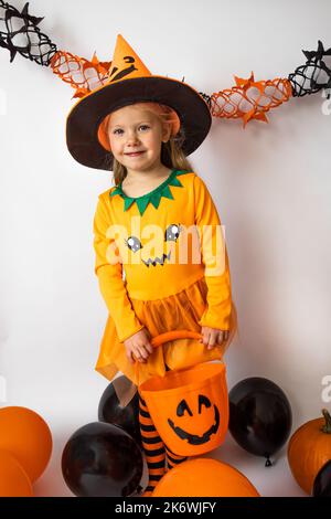 Halloween.A girl dans un costume de citrouille se tient avec un seau sur un fond blanc Banque D'Images