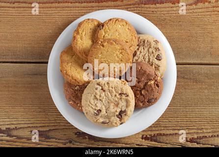 Divers biscuits dans l'assiette sur fond de bois, vue de dessus Banque D'Images