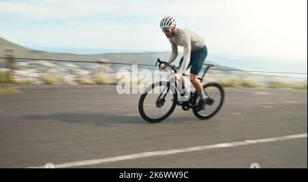 En faisant des kilomètres. Prise de vue en longueur d'un beau homme mature qui fait du vélo à l'extérieur. Banque D'Images