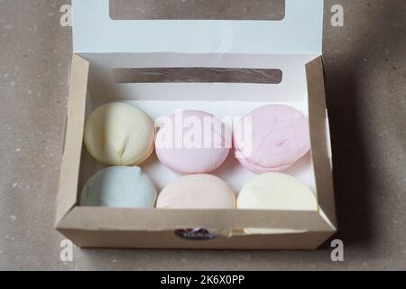 Six guimauves colorées faites à la main dans une boîte en carton sur la table Banque D'Images