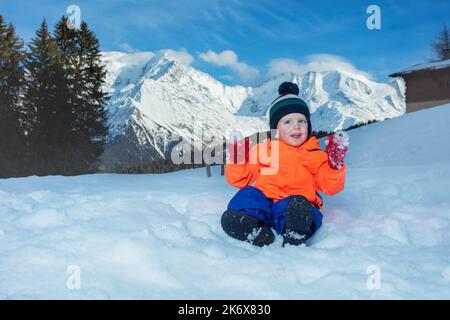 Garçon en tenue d'hiver jouer avec la neige à la montagne sur fond Banque D'Images