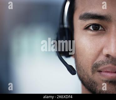 Résolution des problèmes un par un. un jeune agent du service à la clientèle assis seul au bureau et portant un casque. Banque D'Images