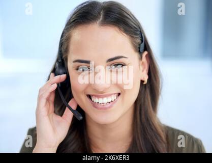 Vous n'aurez pas à mettre la ligne en attente pendant que vous envoyez un message instantané ici. Portrait d'une jeune femme d'affaires utilisant un casque dans un bureau moderne. Banque D'Images