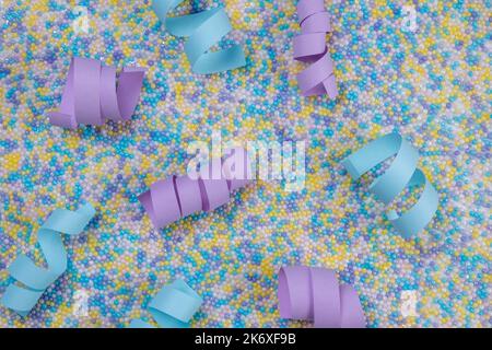 Fond de fête multicolore dans des couleurs pastel délicates avec des arrosettes pour gâteau et des rubans ou serpentins bleus et violets. Banque D'Images