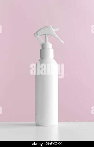 Maquette de bouteille de pulvérisateur à gâchette cosmétique blanche avec fond rose. Banque D'Images