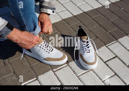 Pieds pour hommes en blanc tous les jours baskets en cuir naturel sur laçage. Banque D'Images