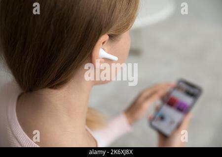 Femme porter des écouteurs sans fil tient le smartphone à l'aide d'une application mobile Banque D'Images