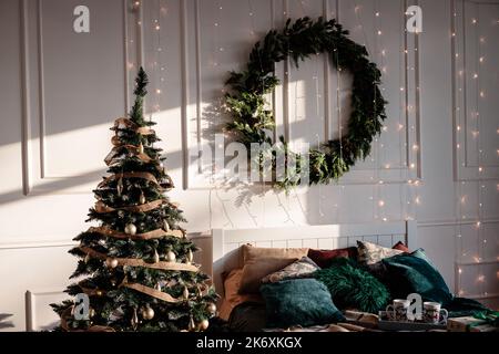 La chambre est décorée pour Noël. Intérieur confortable et lumineux : lit en bois, écossais. Dans la chambre il y a un arbre de Noël décoré avec des jouets et des guirlandes Banque D'Images