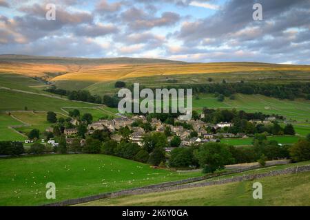 Village pittoresque de Dales (chalets et maisons) niché dans la vallée (pentes abruptes à flanc de colline et terres émergées ensoleillées) - Kettlewell, Yorkshire Angleterre Royaume-Uni. Banque D'Images