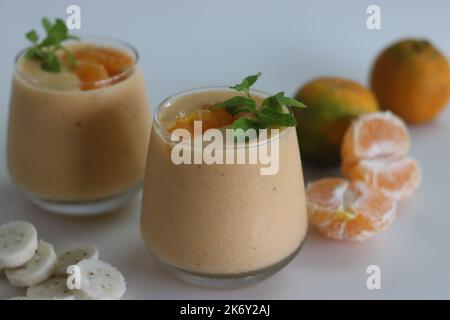 Smoothie à la banane orange. Boisson d'été smoothie fait de bananes congelées et d'orange fraîche dans le lait d'amande, garni de feuilles de menthe. Photo sur fond blanc Banque D'Images