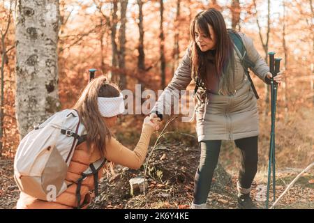 Une fille aidant l'autre à grimper sur l'obstacle pendant la randonnée Banque D'Images