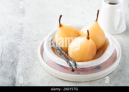 Poires. Poires pochées au sirop. Dessert traditionnel en tranches dans une assiette blanche avec des feuilles et à la maison sur un fond clair. Délicieux dessert pour Banque D'Images