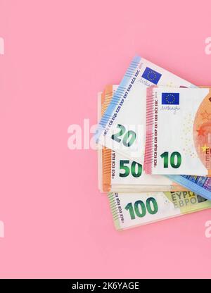 Paquet de billets en euros. 10 euros à l'avant et détails de 20, 50, 100 à l'arrière. Argent sur fond rose Banque D'Images