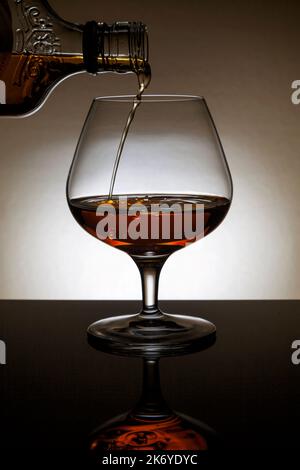 Verser un Cognac dans un verre de fond. Banque D'Images