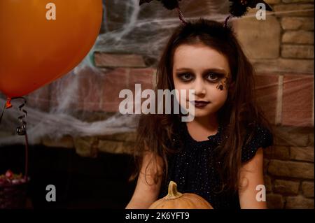 Petite fille, qui ressemble à une sorcière en costume de carnaval de sorcière appréciant les préparations d'Halloween. Enchanteresse adorable Banque D'Images