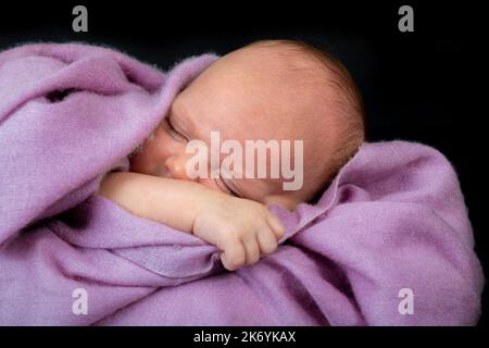 Un tout petit bébé endormi sur une couverture en cachemire lilas Banque D'Images