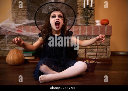 Petit enfant en costume de sorcière. Fête d'Halloween. Adorable petite fille dans le chapeau de magicien. Le sort de l'espoir fonctionne. Vacances d'automne Banque D'Images