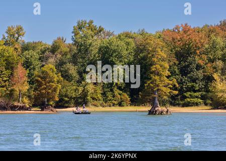 Trois hommes pêchent à partir d'un petit bateau sur le lac Kentucky au début de l'automne. Les feuilles commencent à changer de couleur début octobre. Banque D'Images