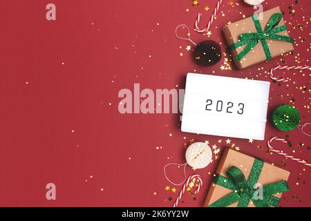Visionneuse avec 2023 numéros. Cadre en décorations du nouvel an sur fond rouge avec espace pour les copies. Banque D'Images