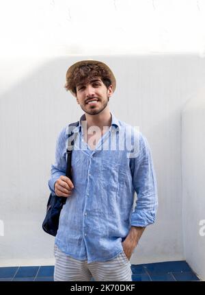 Portrait d'un jeune homme italien avec un chapeau de paille regardant l'appareil photo. Banque D'Images